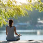 Schöne Frau praktiziert Yoga am Wasser im Park.