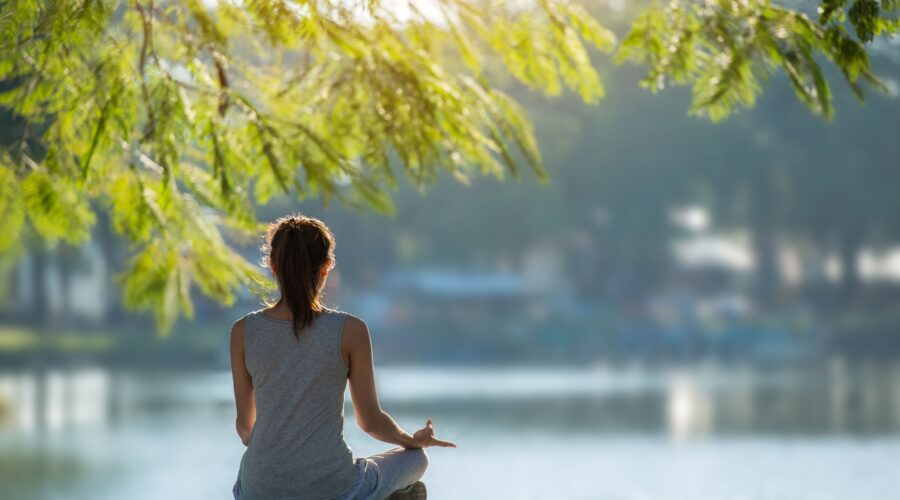 Schöne Frau praktiziert Yoga am Wasser im Park.